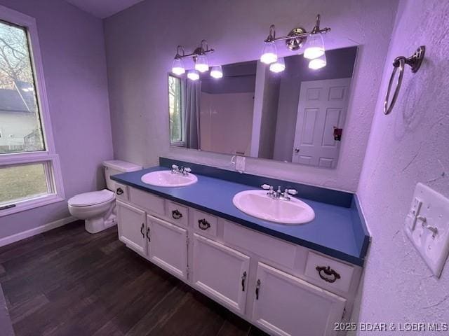 full bathroom with double vanity, toilet, wood finished floors, and a sink