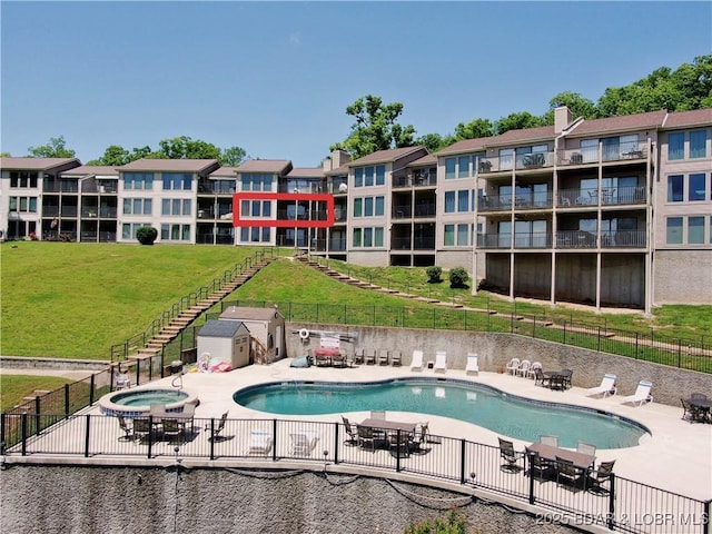 community pool with a patio, a community hot tub, a yard, and fence