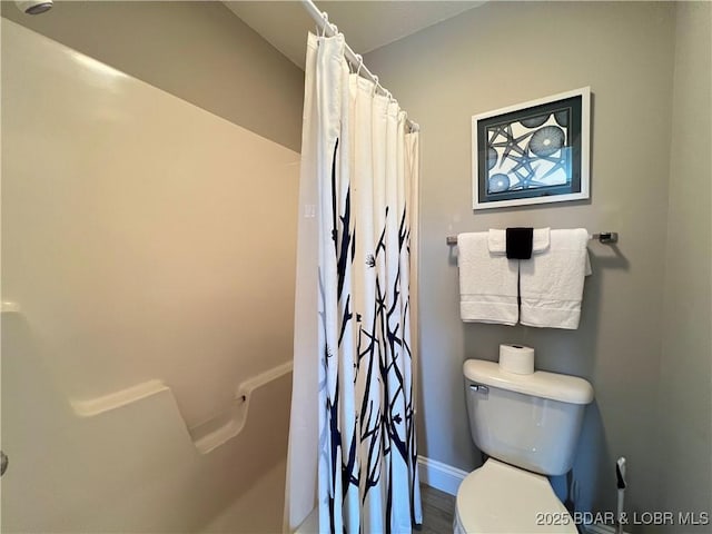 bathroom with baseboards, toilet, and a shower with curtain