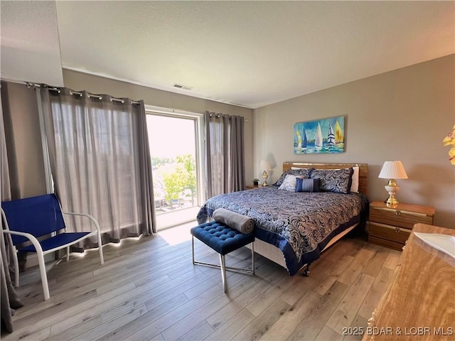 bedroom featuring visible vents, wood finished floors, and access to exterior