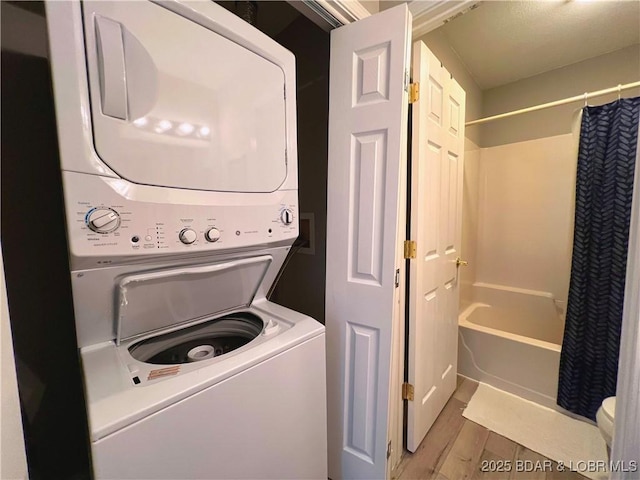 washroom with laundry area, stacked washer / drying machine, and light wood finished floors