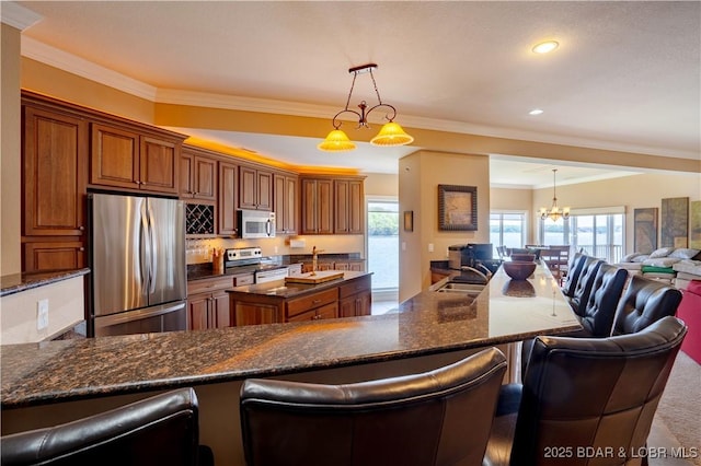 kitchen featuring crown molding, open floor plan, brown cabinetry, stainless steel appliances, and a sink