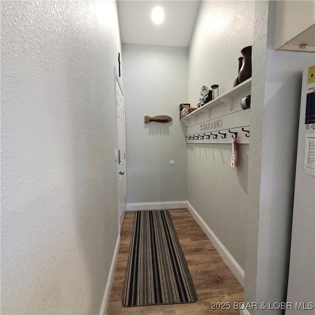 mudroom featuring wood finished floors, baseboards, and a textured wall