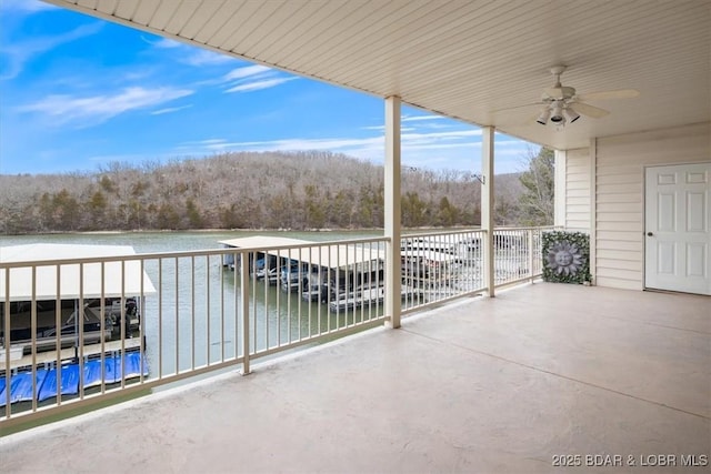 view of patio / terrace with a view of trees, a ceiling fan, and a water view