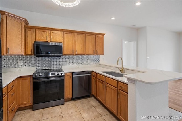 kitchen featuring tasteful backsplash, light countertops, brown cabinets, a peninsula, and stainless steel appliances