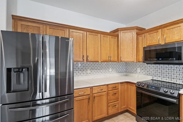 kitchen featuring light tile patterned flooring, decorative backsplash, appliances with stainless steel finishes, and light stone countertops