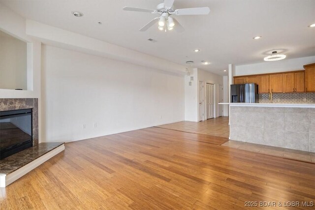 unfurnished living room featuring a ceiling fan, recessed lighting, light wood-style floors, and a high end fireplace