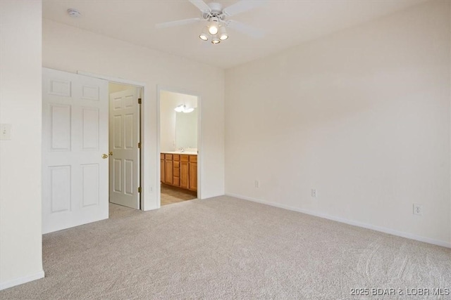 unfurnished bedroom featuring baseboards, light colored carpet, and ensuite bathroom