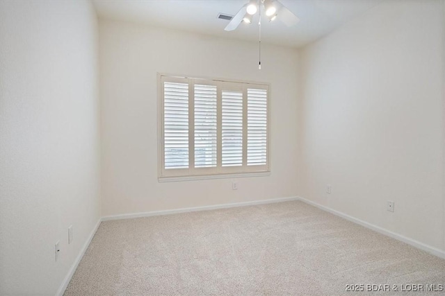 carpeted spare room with visible vents, baseboards, and a ceiling fan