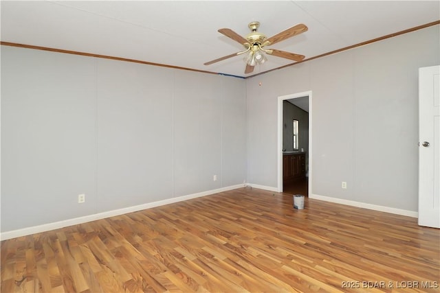 spare room with baseboards, light wood-type flooring, ceiling fan, and ornamental molding