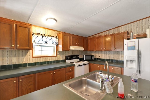 kitchen featuring wallpapered walls, under cabinet range hood, vaulted ceiling, white appliances, and a sink