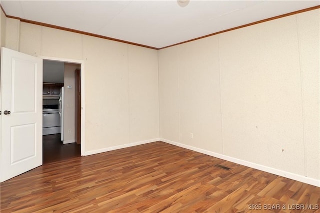 empty room featuring visible vents, crown molding, baseboards, and wood finished floors