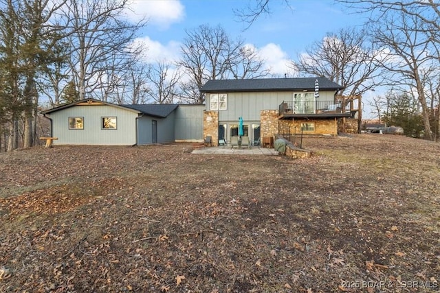 back of house with a wooden deck and a patio