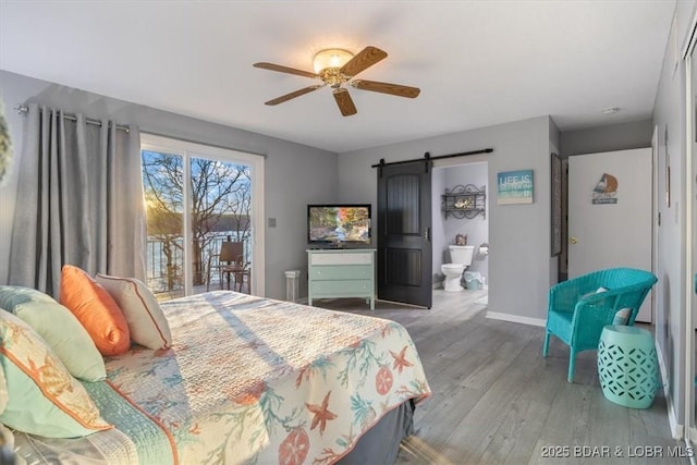 bedroom with access to exterior, wood finished floors, a barn door, baseboards, and ceiling fan