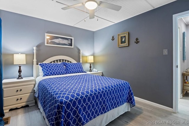 bedroom featuring baseboards, wood finished floors, and a ceiling fan