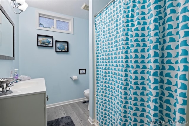 full bathroom featuring vanity, wood finished floors, visible vents, baseboards, and toilet