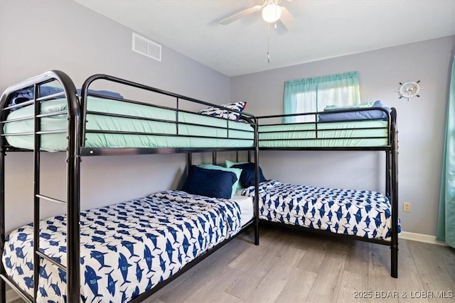 bedroom with visible vents, a ceiling fan, baseboards, and wood finished floors