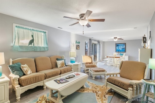 living area featuring a ceiling fan, wood finished floors, and visible vents