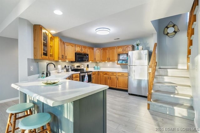 kitchen featuring stainless steel appliances, a kitchen bar, a peninsula, and light countertops