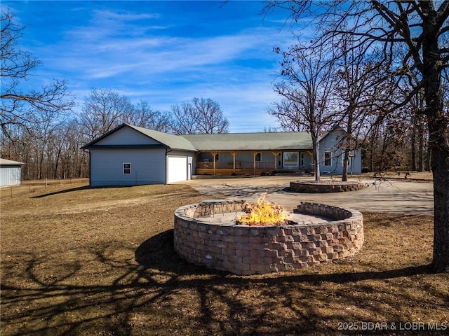 back of house with an attached garage, a fire pit, and driveway