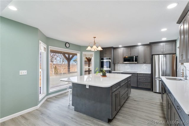 kitchen featuring a center island, light wood-style floors, appliances with stainless steel finishes, light countertops, and decorative backsplash