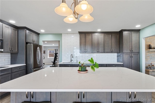 kitchen with a breakfast bar, a spacious island, freestanding refrigerator, and a sink