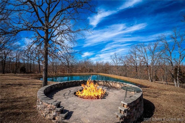 view of pool featuring a forest view and a fire pit