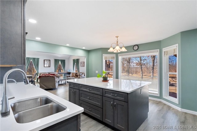 kitchen with decorative light fixtures, light countertops, light wood-style floors, a notable chandelier, and a sink