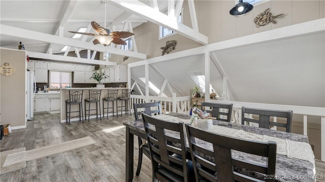 dining room featuring ceiling fan, beam ceiling, high vaulted ceiling, and light wood-style flooring