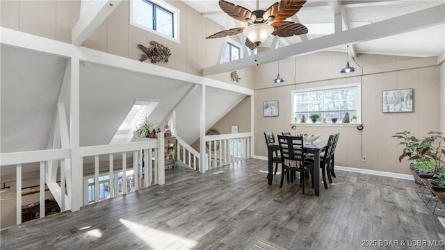 unfurnished dining area featuring lofted ceiling with beams, baseboards, wood finished floors, and ceiling fan