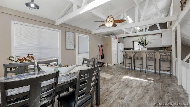 dining space with light wood finished floors, lofted ceiling with beams, and a ceiling fan