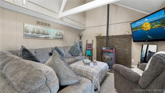 living area with visible vents, vaulted ceiling with beams, and a wood stove