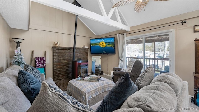 living room featuring lofted ceiling with beams, a wood stove, and a ceiling fan