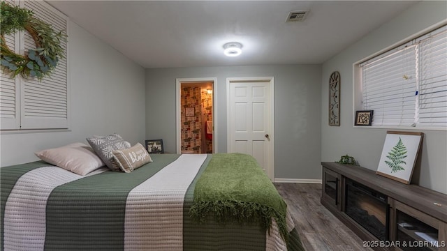 bedroom with dark wood-style floors, visible vents, and baseboards