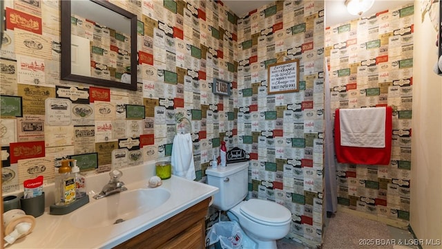 bathroom with wallpapered walls, toilet, and vanity