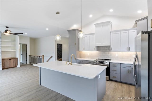 kitchen with light wood-type flooring, lofted ceiling, appliances with stainless steel finishes, custom exhaust hood, and a sink