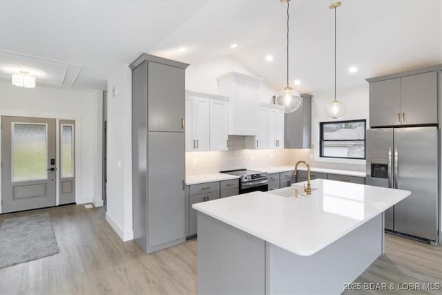 kitchen with gray cabinets, a sink, light countertops, appliances with stainless steel finishes, and tasteful backsplash