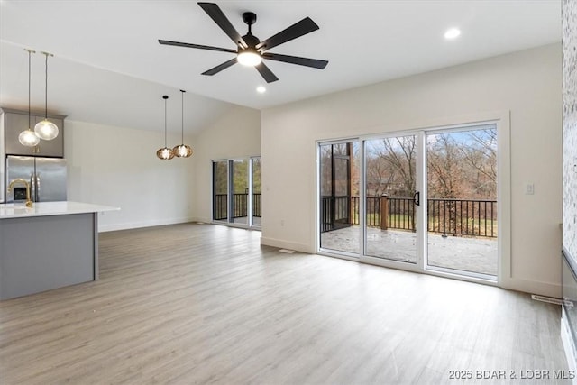 unfurnished living room with a ceiling fan, lofted ceiling, light wood-style floors, and baseboards