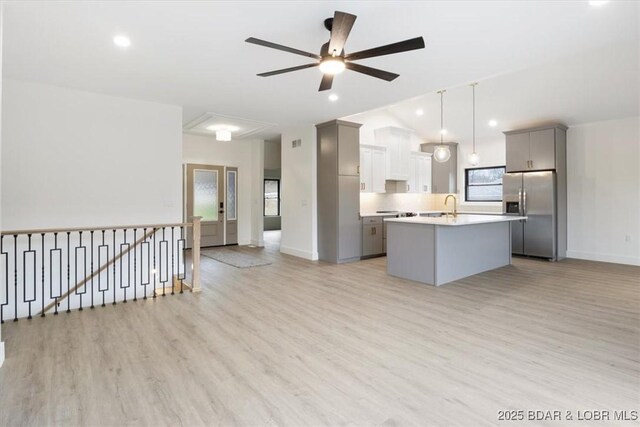 kitchen with a kitchen island with sink, stainless steel fridge, gray cabinets, and a sink