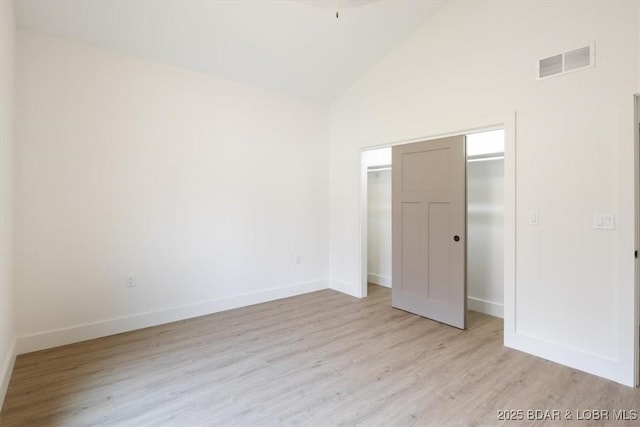 unfurnished bedroom featuring visible vents, baseboards, light wood-style floors, and high vaulted ceiling