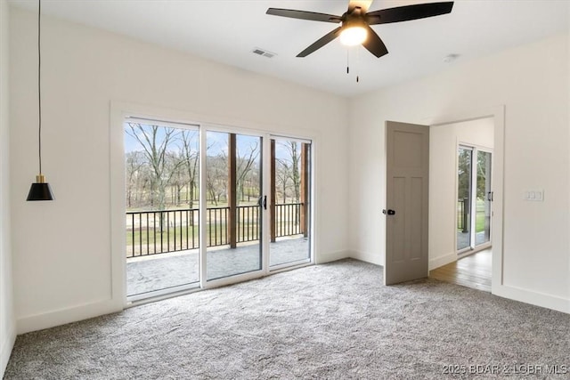 carpeted empty room with visible vents, baseboards, and ceiling fan