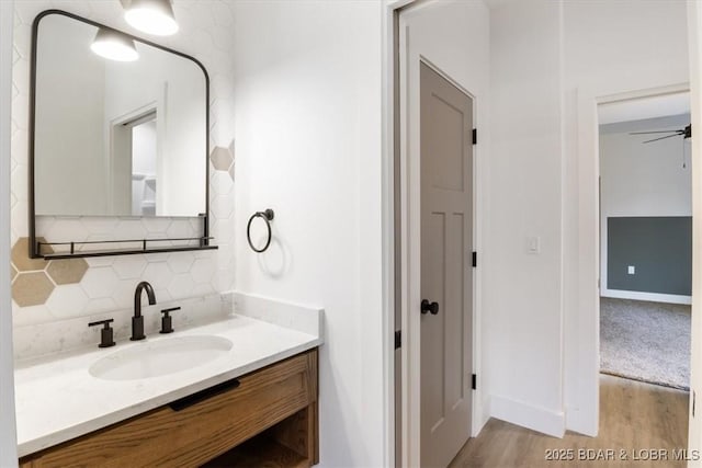 bathroom with a ceiling fan, tasteful backsplash, wood finished floors, baseboards, and vanity