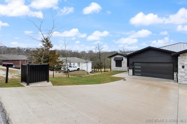 view of front of house with concrete driveway, a garage, stone siding, and a front yard