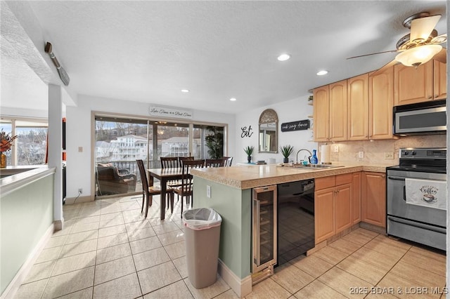 kitchen featuring a sink, tasteful backsplash, appliances with stainless steel finishes, a peninsula, and light countertops