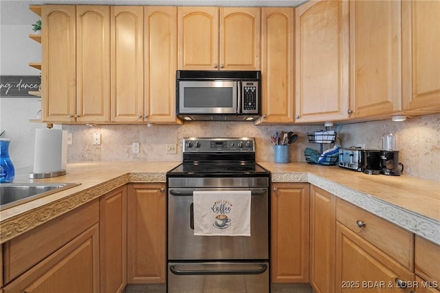 kitchen featuring light brown cabinets, decorative backsplash, appliances with stainless steel finishes, and light countertops