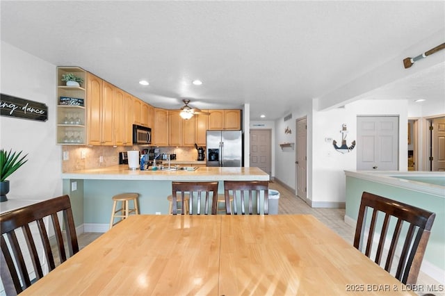 kitchen featuring open shelves, a peninsula, light countertops, appliances with stainless steel finishes, and tasteful backsplash