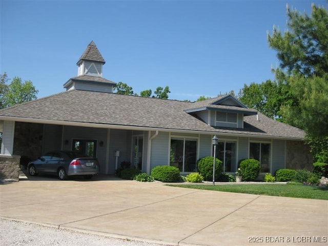 view of front facade featuring an attached carport, concrete driveway, and a shingled roof