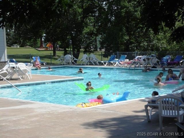 community pool with a patio and fence