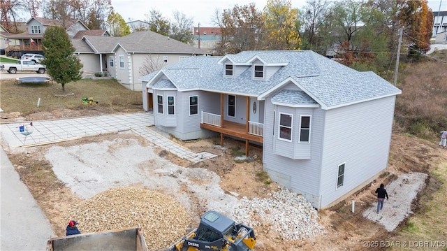 view of front facade with roof with shingles and driveway