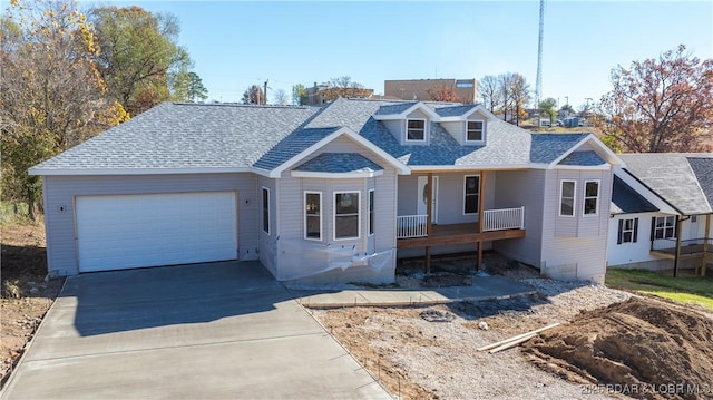 view of front of home featuring covered porch, an attached garage, concrete driveway, and a shingled roof